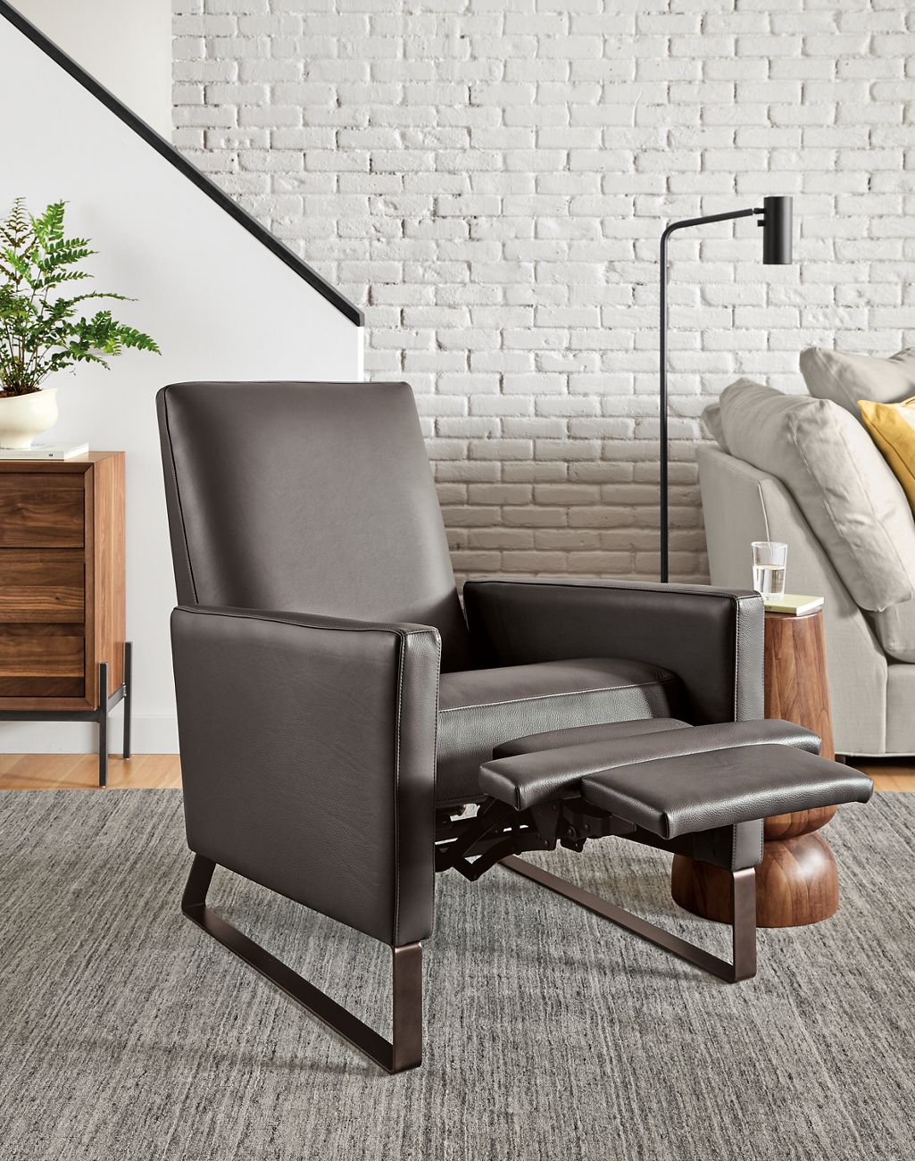 Detail of Arlo Thin-Arm Recliner in Urbino Smoke Leather with steel sled base with foot rest extended.