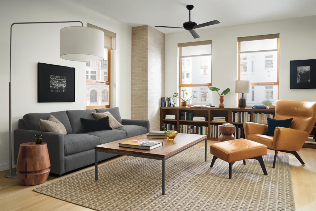 Living room setting with Linger 91-inch Sofa in Flint Charcoal fabric, Boden Chair and Ottoman in Vento Camel leather and Parson Coffee Table in Natural Steel and Walnut.