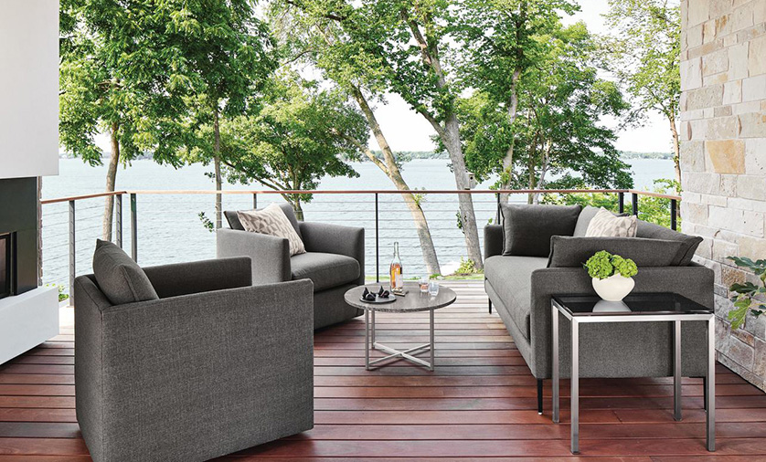 Palm outdoor sofa and swivel chairs with Classic table and Parsons table on a wood deck overlooking a lake.