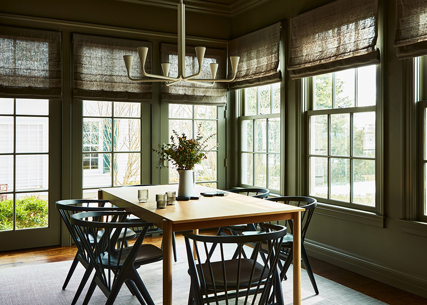 Breakfast room with taupe walls, oak table, black spindle chairs and plaster chandelier.