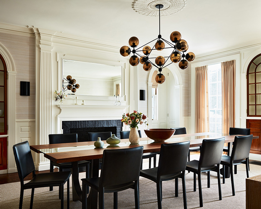 Dining room in a MA estate with grass cloth wall, long custom table, leather chairs and modern glass chandelier.