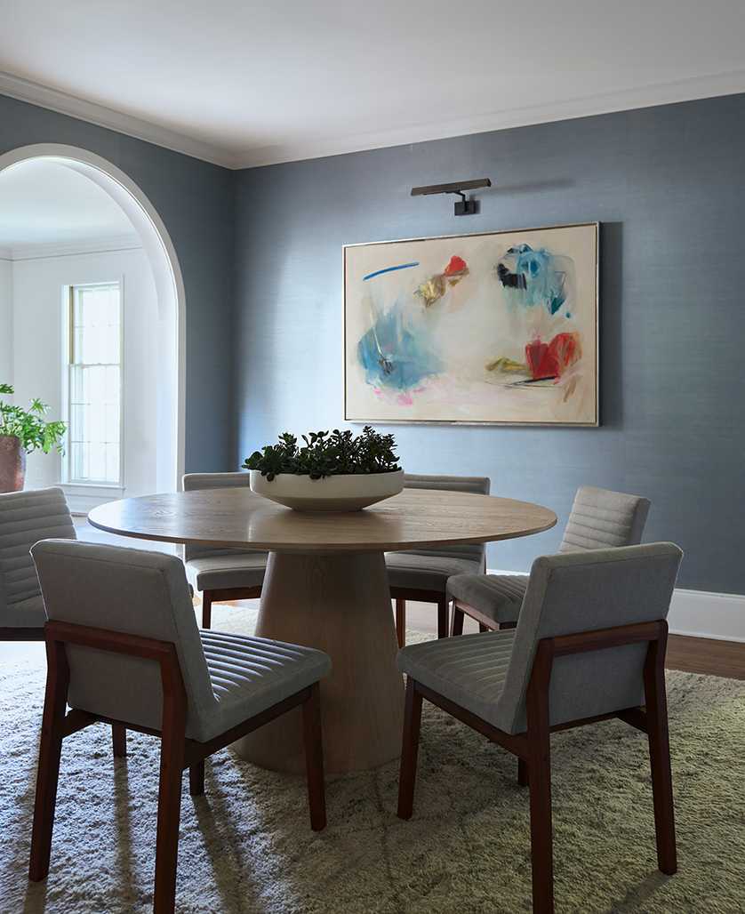 Dining room in a Hingham home with blue grass cloth wall, oak pedestal table, abstract wall art and Room & Board chairs.