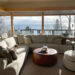Living room furniture in sunlit cabin looking over Lake Superior